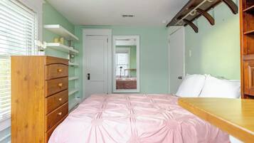Ein Schlafzimmer mit Bett, Holzkommode und Regalen.