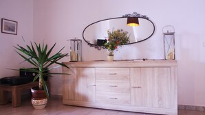 A wooden cabinet with a mirror, a potted plant, and a small table with a lamp.