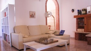 A living room with a sofa, a coffee table with a chess set, a bookshelf, and a fireplace.