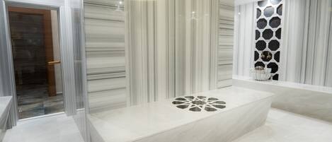 A modern bathroom with a large bathtub, a glass shower enclosure, and a decorative wall panel.