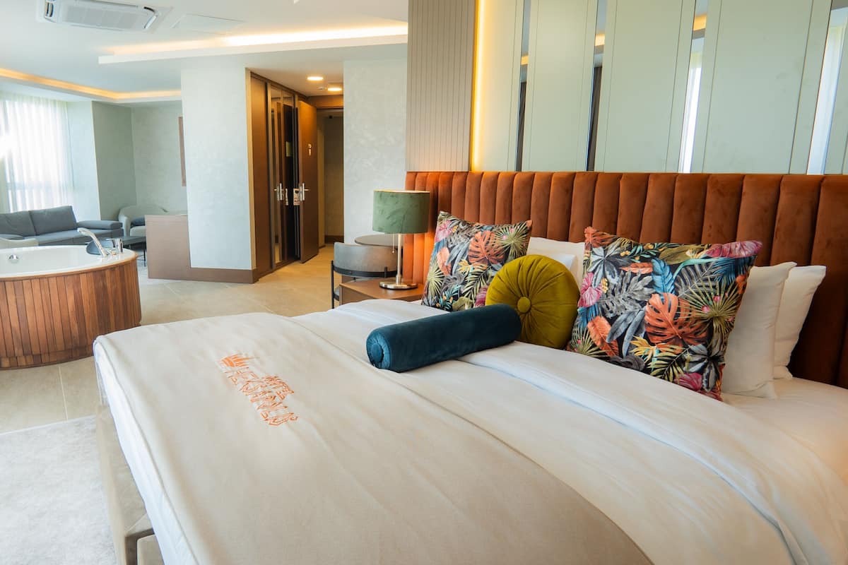 A hotel room with a large bed, a separate bathroom with a bathtub, a desk, and a chair.