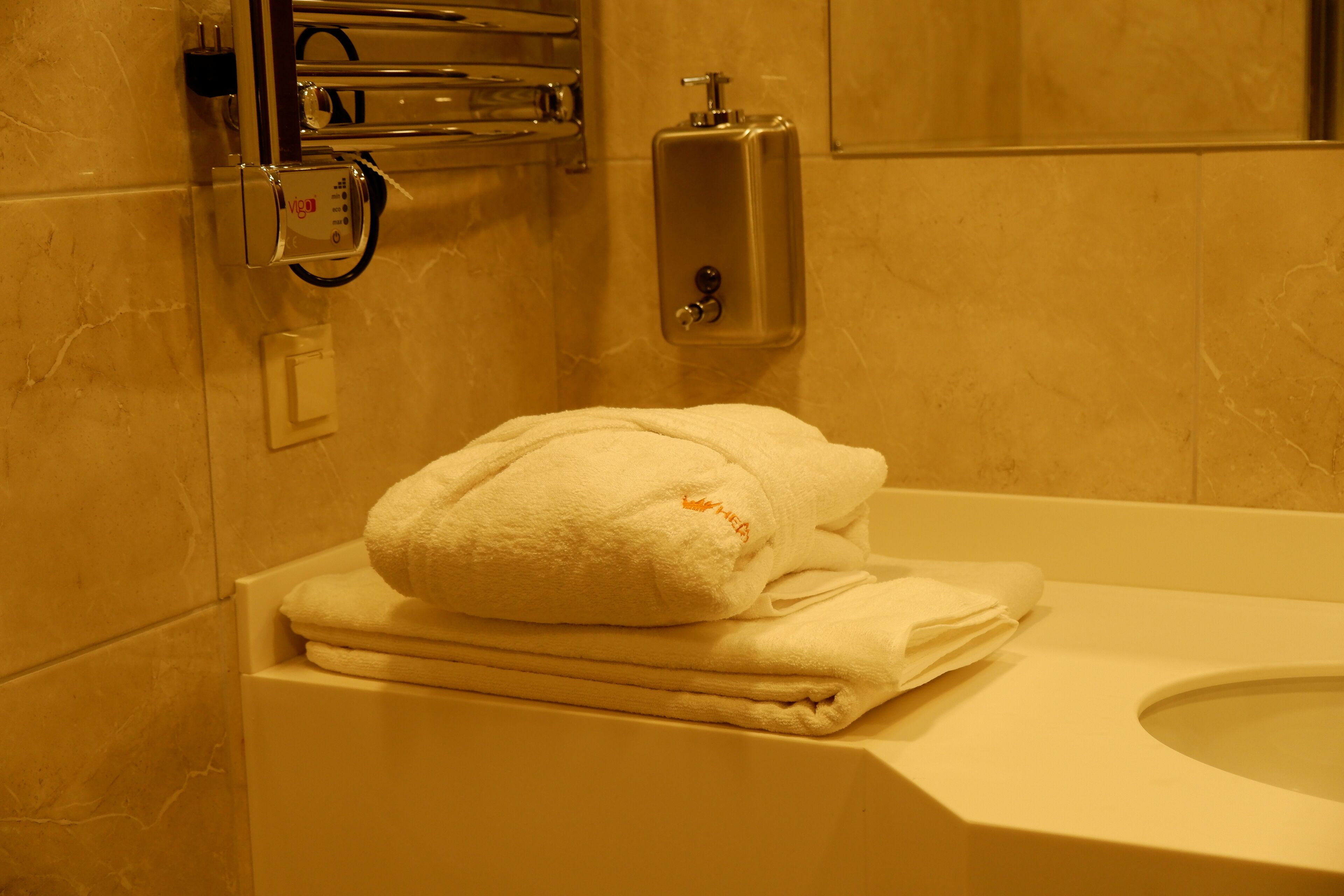 Une salle de bain avec des toilettes blanches, un distributeur de serviettes et un porte-serviettes.