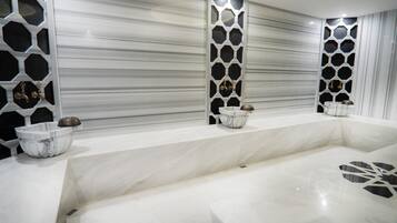 A modern bathroom with a marble vanity, a large mirror, and decorative wall panels.