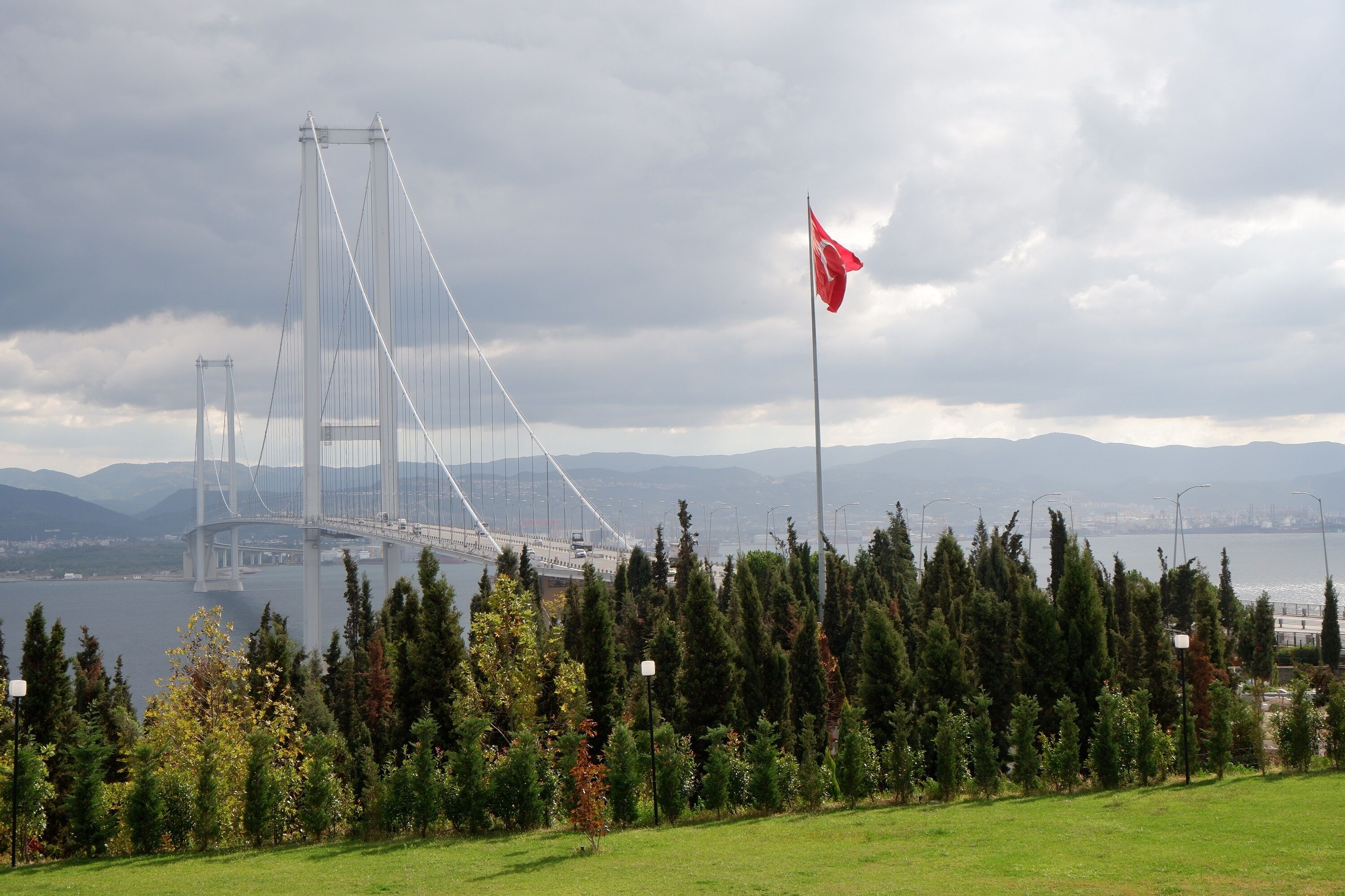 A large suspension bridge with a flag in the foreground.