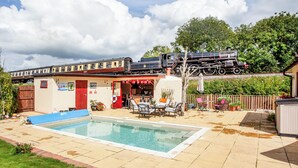 A pool area with a dining setup and a train track above.