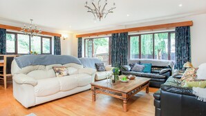 A spacious living room with two sofas, a wooden coffee table, and a chandelier.