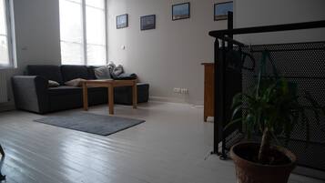 Un salon avec un canapé gris, une table basse en bois et une plante en pot.