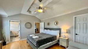 Ein Schlafzimmer mit einem Bett, einem Nachttisch, einem Deckenventilator und einer Tür.