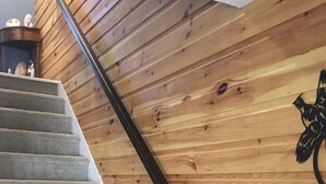 Una escalera de madera con barandilla negra que conduce a un rellano con un detalle decorativo en la pared.