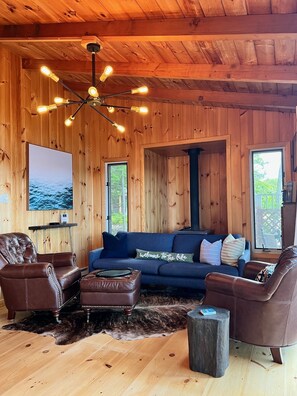 Relax in a cozy space with a comfortable sofa, armchairs, and a large window offering a view of the outdoors.