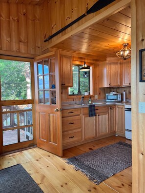 Kitchen with a view of the surrounding greenery, featuring a microwave, sink, and wooden cabinets.