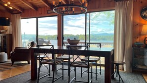 Interior de madeira com uma mesa de jantar, cadeiras e vista para um lago.
