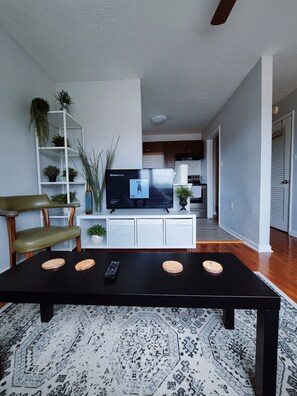 A modern living room with a black coffee table, a television, and a white entertainment unit. - Stylish & Central - Walk to UK Campus/Hospital, Mins to DT/Rupp/Keeneland (Lexington)