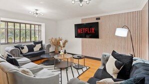 A modern living room with a sofa set, a coffee table, and a television mounted on the wall. - Stunning Coastal Retreat - Indoor Pool - Sauna (Hunmanby)