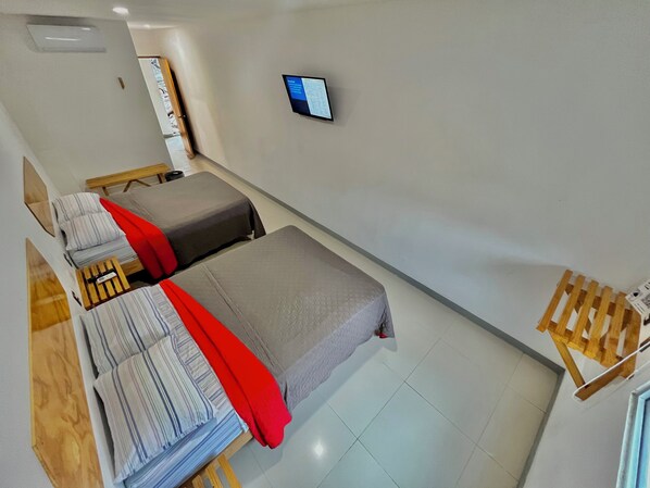 A hotel room with two beds, a small TV on the wall, and a wooden side table.