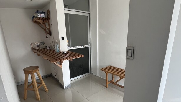 Cocina moderna con encimera de madera, taburetes y una puerta corredera que da a otra habitación.