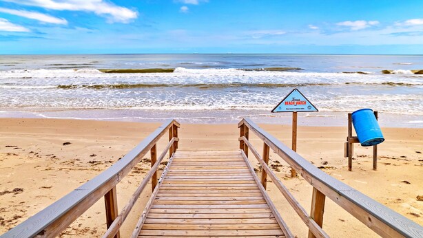 A wooden boardwalk leading to a beach with a sign indicating a beach watch area. - Beach Please (Surfside Beach)