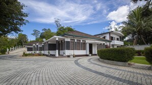 A modern building with a curved roof, a paved driveway, and surrounding greenery. - Bandarawela City Bungalow (Bandarawela)