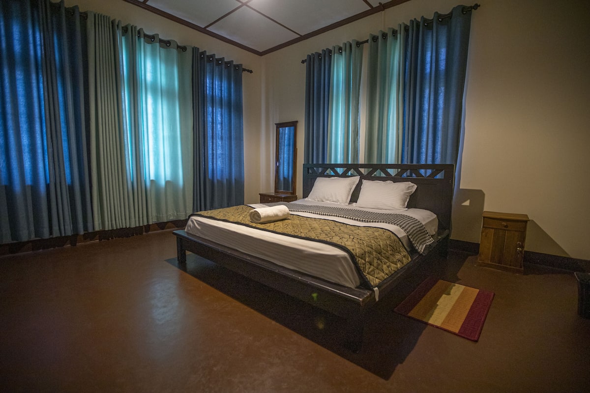 A neatly made bed with a quilt, a wooden nightstand, and a small wooden cabinet.