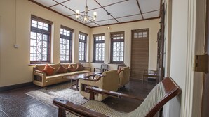 A spacious room with a sofa, armchairs, and a wooden coffee table. - Bandarawela City Bungalow (Bandarawela)