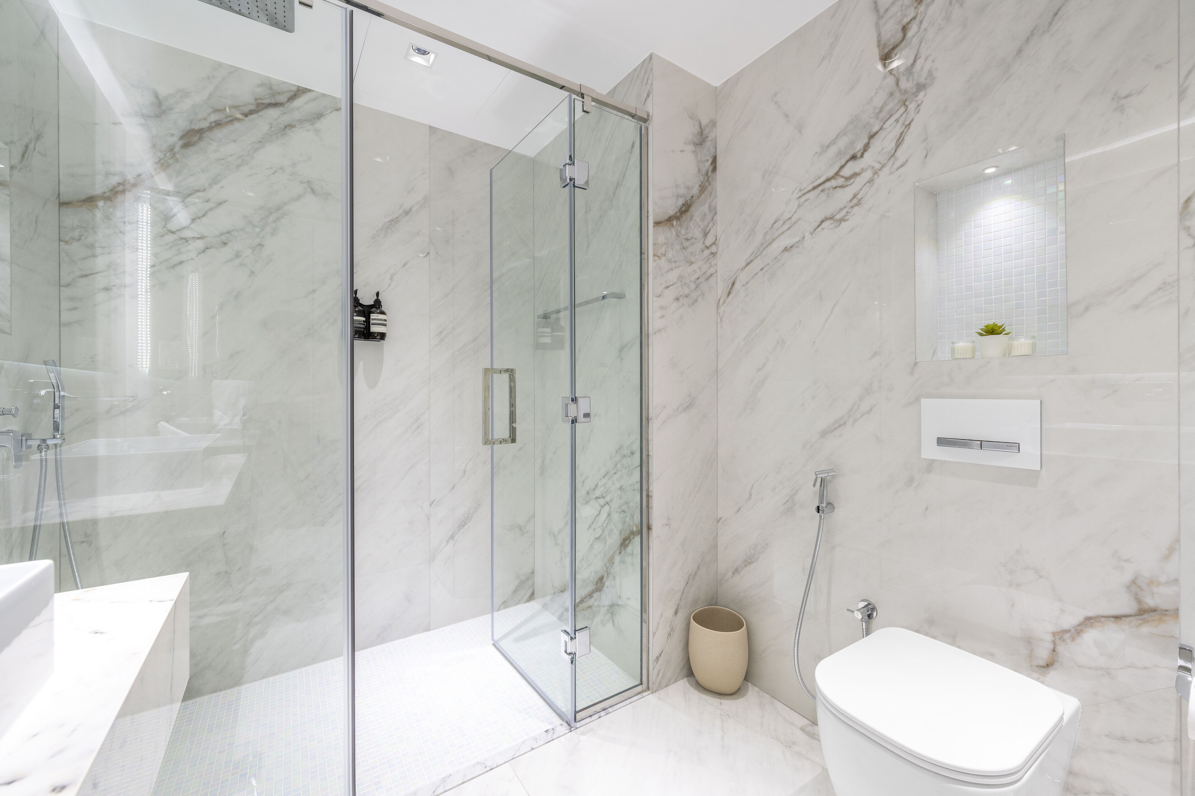 A modern bathroom with a glass-enclosed shower, a toilet, and a sink.