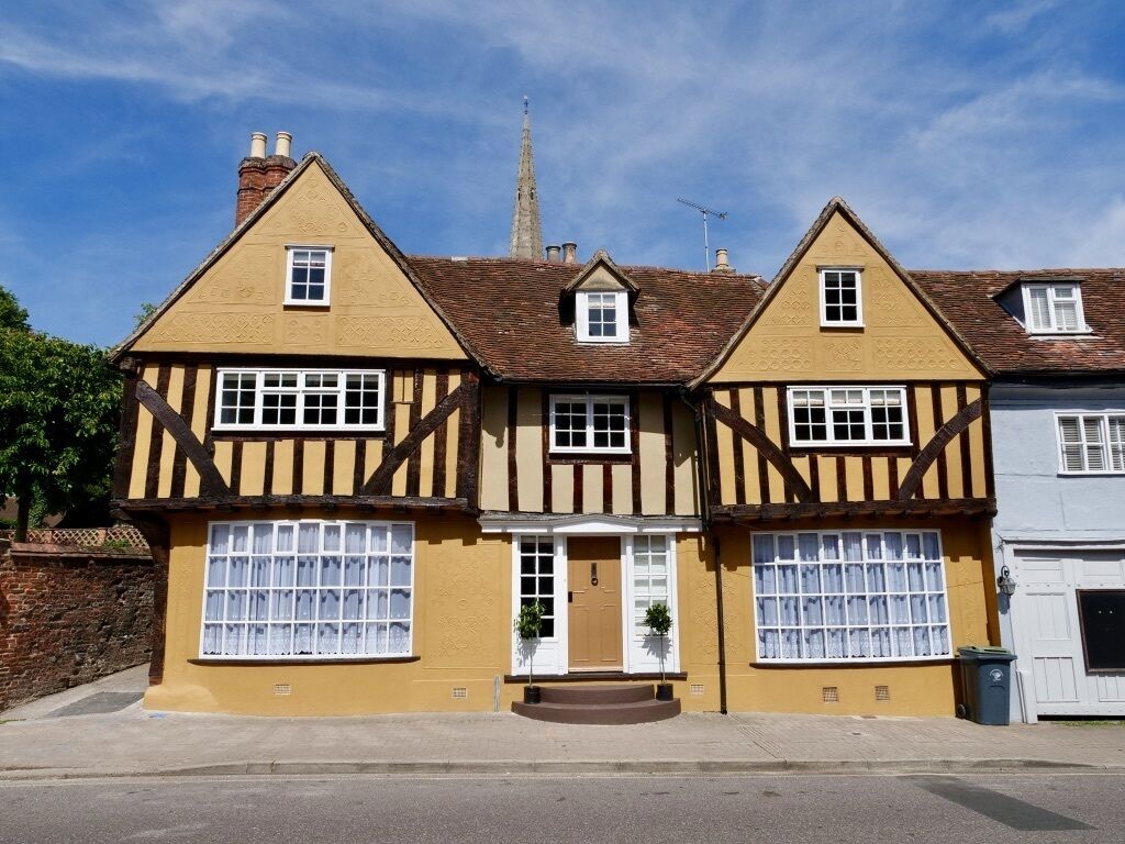 Ein traditionelles Haus im Tudor-Stil mit einer symmetrischen Fassade, zwei Schornsteinen und einer zentralen Tür mit einer kleinen Veranda.
