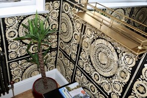 A room with patterned wallpaper, a potted plant, and a book on a table.