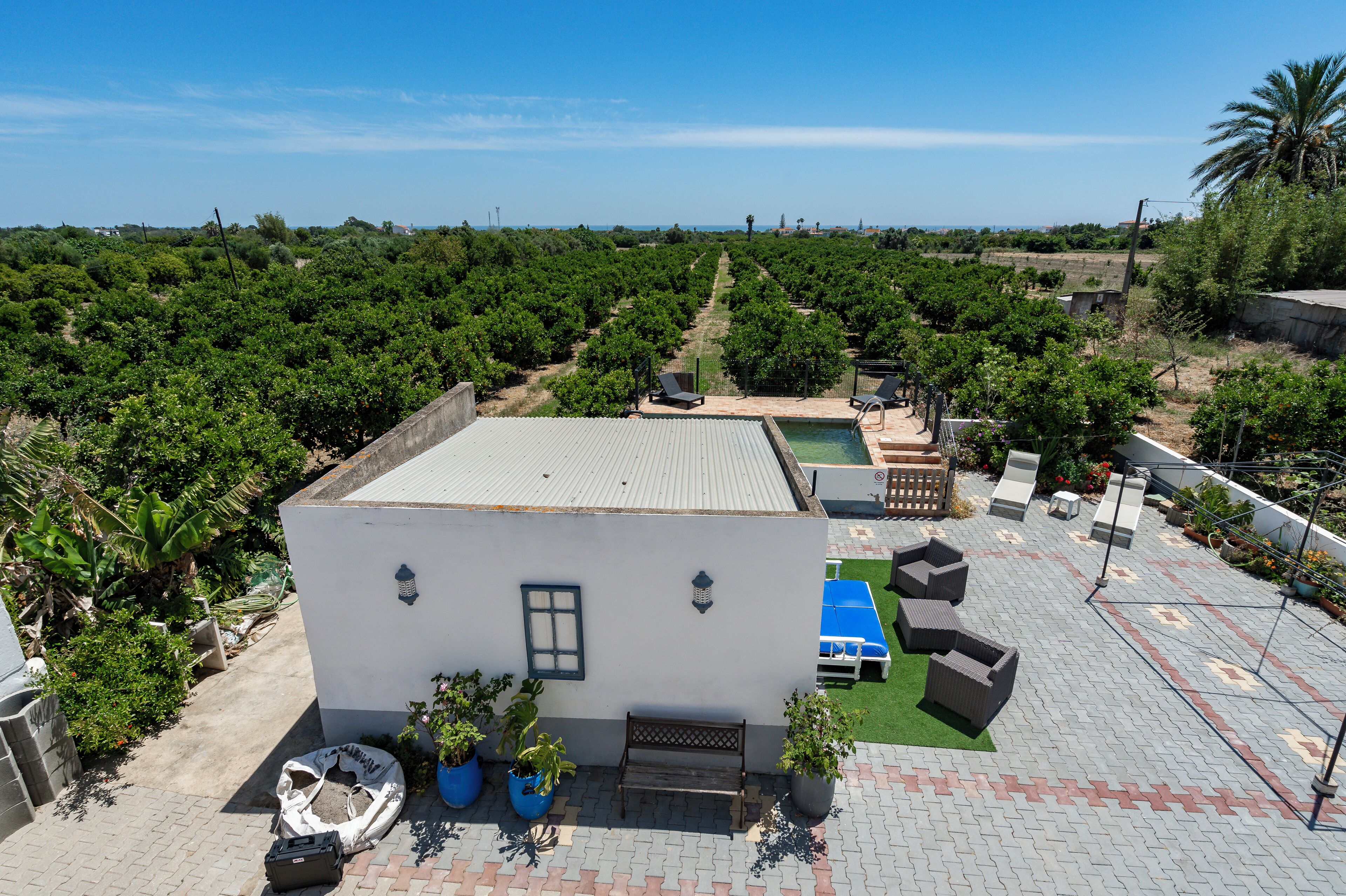 A rooftop terrace with a pool, outdoor seating, and a view of a vineyard.