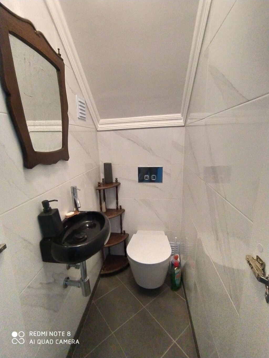Un baño pequeño con inodoro, lavamanos y espejo.