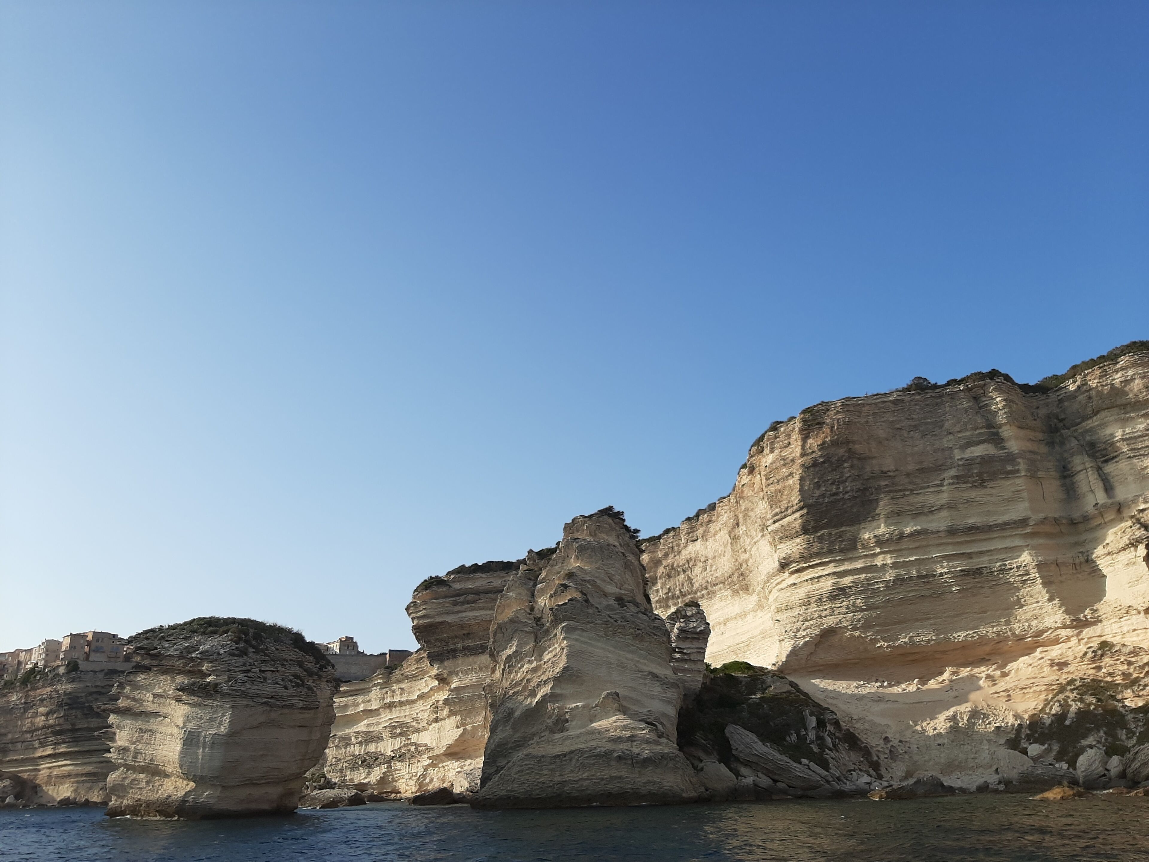 Eine Küstenklippe mit schichtartigen Felsformationen und blauem Himmel.