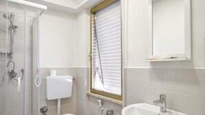 Et moderne badeværelse med bruser, toilet og vask.