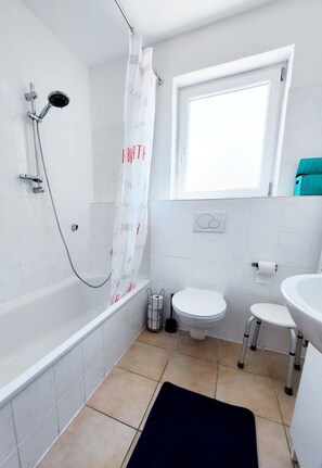 A bathroom with a bathtub, toilet, and sink. - Gemütliche Ferienwohnung in Ruhiger Lage (Sachsenheim)