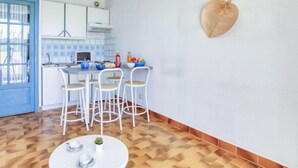 Moderni keittiö, jossa on valkoiset kaapit, sinisellä kehyksellä varustettu ikkuna ja valkoisilla tuoleilla varustettu ruokailutila.