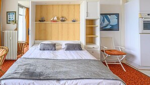 A hotel room with a bed, a chair, a desk, a radiator, and a painting on the wall. - Les Trois Iles by Interhome (Quiberon)