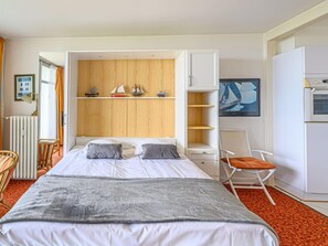 Une chambre d’hôtel avec un lit, une chaise, un bureau, un radiateur et un tableau au mur.