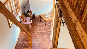 A wooden staircase leading to a room with a brick floor, a small table, and a window. - Walnußhof im Spreewald (Schmogrow-Fehrow)