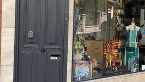 A storefront with a dark wooden door and a large window displaying various items. - La Vie en Rose (Prades)