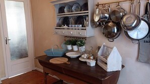A kitchen with wooden cabinets, a hanging pot rack, and various kitchen utensils. - La Vie en Rose (Prades)