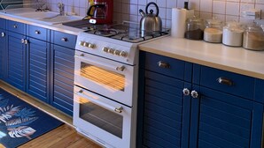 A kitchen with white cabinets, a stove, and a coffee maker. - La Vie en Rose (Prades)