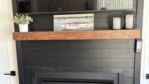 Una chimenea con repisa de madera que exhibe un cartel decorativo y dos jarrones.