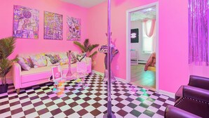 Una habitación con piso a cuadros, pared rosa y ventilador de techo.