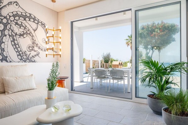 A modern living room with a large glass door leading to an outdoor patio with a dining set.