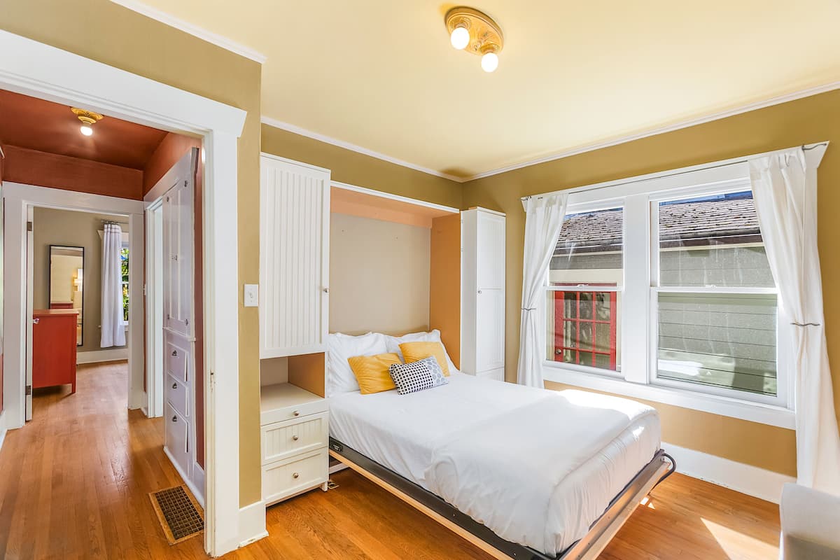 Quarto com cama, closet espaçoso e janela com cortinas.
