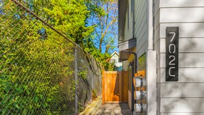 A gated entrance with a wooden gate, a mailbox, and a house number sign. - The Sweetest Hill - 81 Walkscore (Seattle)