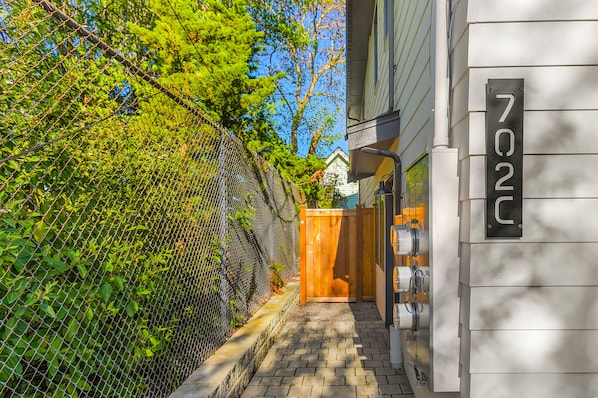 A gated entrance with a wooden gate, a mailbox, and a house number sign.