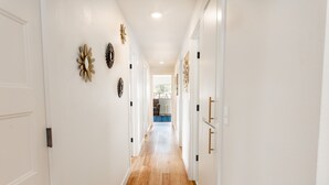 Un couloir aux murs blancs, au plancher en bois et agrémenté d’appliques murales décoratives.