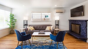 Un salon moderne comprenant un canapé, deux fauteuils, une table basse et une cheminée.