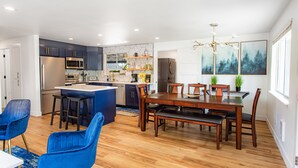 Une cuisine moderne avec un îlot central, des chaises bleues et une table à manger avec des chaises en bois.