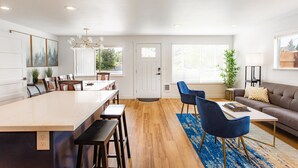 Une cuisine moderne dotée d’un grand îlot central, de planchers en bois et d’un coin repas avec des chaises bleues.