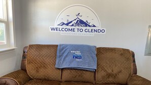 Um sofá acolchoado marrom com uma placa que diz 'Welcome to Glendo' em cima.